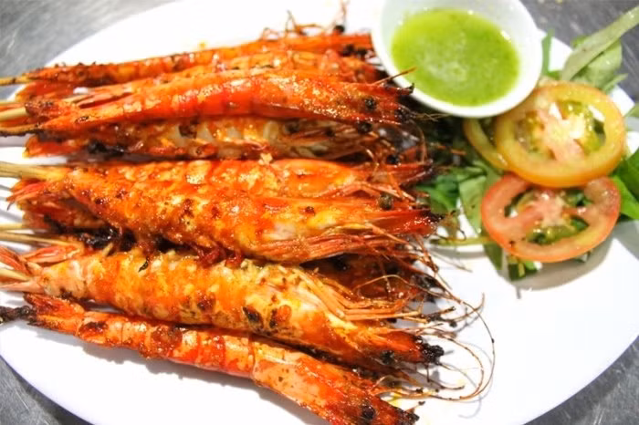 Các nguyên liệu giã nhuyễn rồi phi thơm cùng dầu ăn, thêm mắm ruốc vào đảo, rồi cho nước cốt dừa vào chung. Thêm nước vào rồi nấu sôi, nêm nước mắm, muối, đường sao cho hợp khẩu vị. Cho tôm đã bóc vỏ vào nấu chín. Cuối cùng cho nước cốt chanh, húng quế trộn lên cho thật đều. Món này dùng nóng với cơm hoặc bánh mì. Ảnh: banhtranghubinh.com.