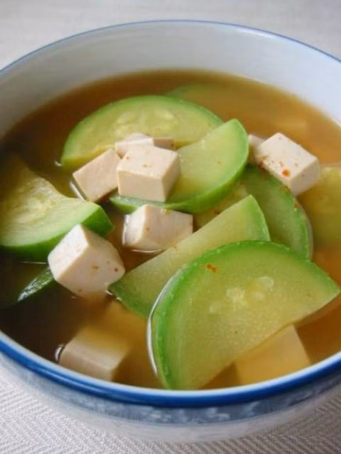 Canh bí ngòi đậu phụ. Bí ngòi mẹ nạo vỏ, cắt ra bỏ ruột rồi băm nhỏ tùy thuộc độ ăn thô của con. Đậu non mẹ có thể thái miếng nhỏ hoặc để nguyên miếng hoặc dằm nát. Phi phần đầu trắng hành tươi thơm rồi cho bí vào xào qua, nêm chút gia vị và cho nước vào đun, gần chín mẹ cho đậu phụ vào. Lúc này bé có thể làm quen với các loại rau gia vị như hành, riêu, ngổ... tùy ý mẹ cho vào. Ảnh: Lanvaobep.