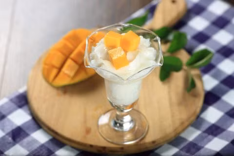 Cho gạo, đường, nước cốt dừa, kem tươi và ½ chén nước dừa tươi trộn đều, nấu lửa vừa cho đến khi gạo nở tơi, để nguội. Cho pudding gạo sữa dừa vào ly, thêm dừa non, trang trí xoài cắt hạt lựu thêm phần hấp dẫn. Ảnh: Bepgiadinh.