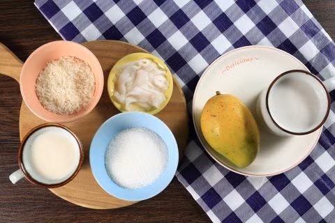 Bánh pudding gạo sữa dừa. Nguyên liệu gồm ½ chén gạo, 1/3 chén đường, 200ml nước cốt dừa, 100ml kem tươi, 1 quả dừa non, 1 quả xoài. Đầu tiên nạo phần thịt dừa, rót nước để riêng. Ảnh: Bepgiadinh.