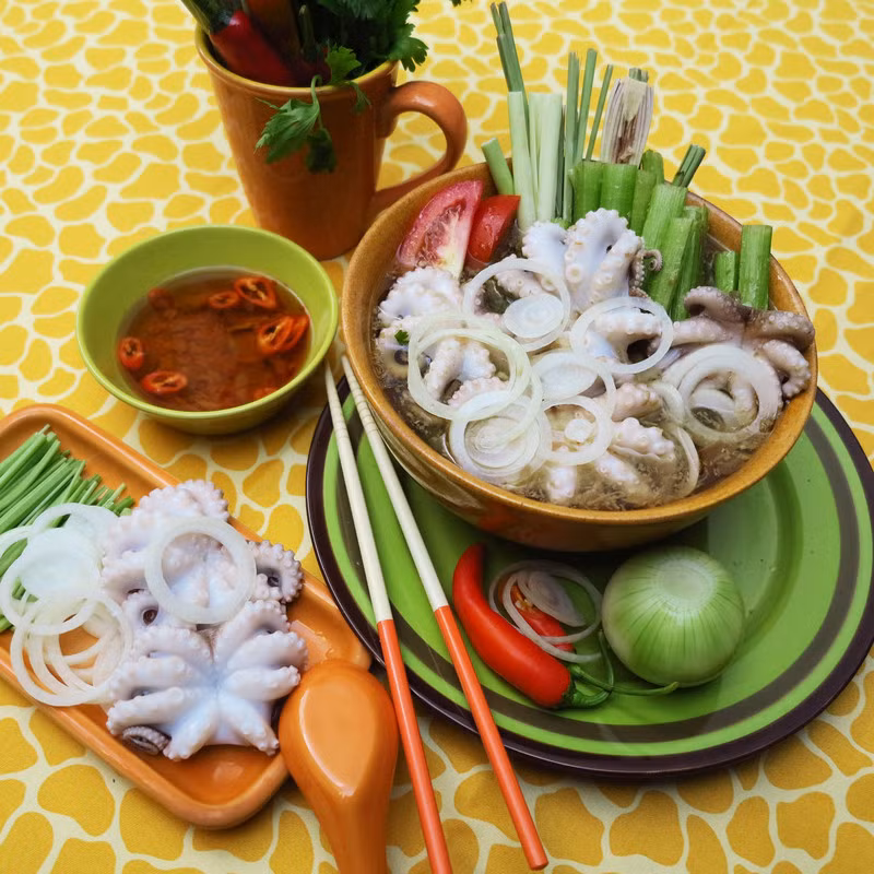 Trang trí các loại rau (đã rửa sạch) ra đĩa. Lấy 1 bếp gas mini hay bếp từ bắt nồi nước dùng lên, nước sôi cho bạch tuộc vào nhúng, ăn kèm bún, mì, rau và nước chấm. Ảnh: BepGiaDinh.com.