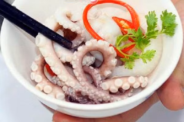 4. Bạch tuộc hấp. Nguyên liệu: Bạch tuộc, chuối chát, rau húng. Bạch tuộc lấy túi mật rửa sạch vớt ra rổ ráo nước. Đem hấp chín. Rau húng rửa sạch. Ảnh: bepdientugiare.com.vn.