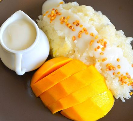 Xới xôi ra đĩa dàn mỏng, bày cả má xoài đã được cắt nhỏ lên trên, sau cùng chan nước cốt dừa và rắc thêm ít vừng rang vàng. Ảnh: ketnoikienthuc.com.