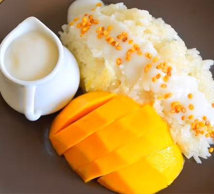 Xới xôi ra đĩa dàn mỏng, bày cả má xoài đã được cắt nhỏ lên trên, sau cùng chan nước cốt dừa và rắc thêm ít vừng rang vàng. Ảnh: ketnoikienthuc.com.