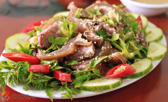 Dê chín tới để ra đĩa cho nguội bớt rồi thái miếng mỏng, cho thịt vào xóc với gia vị, ngổ thái khúc, vừng, nước cốt chanh, mùi tàu. Ăn kèm các loại rau trên. Ảnh: 8monngonmoingay.com.