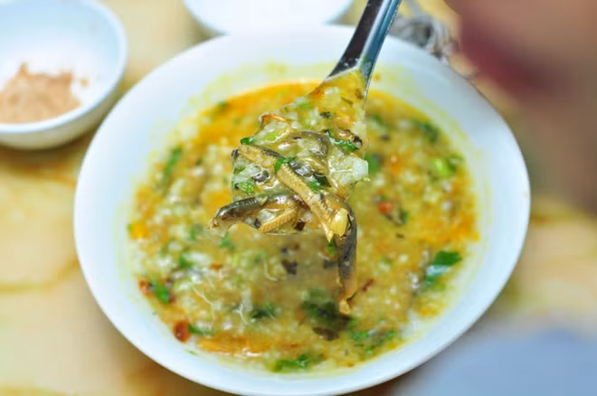 Sau đó cho nước nắm, muối, mì chính vừa ăn, đảo 1 lúc nữa rồi tắt bếp. Múc cháo vào tô, cho đậu phụ chiên, lươn xào, hành phi, rau ngổ lên trên rồi thưởng thức. Ảnh: phunutoday.vn.