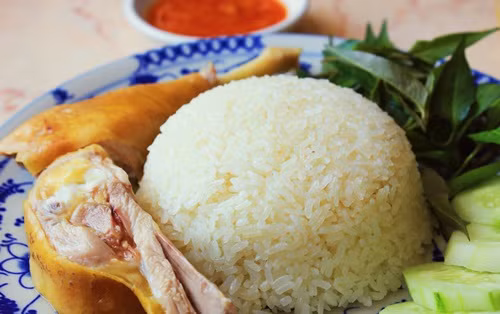 Sau đó cho gà, lá dứa và hành tím vào. Đổ nước ít hơn khi nấu cơm mỗi ngày vì gà sẽ ra nước. Sau đó bật cook để nấu. Cơm chín là gà sẽ vừa chín tới. Pha nước tương, dầu hào, đường và tỏi ớt băm để làm nước sốt ăn kèm. Ảnh: Ngonngon.