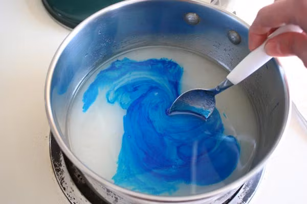 Khi hỗn hợp bắt đầu sôi. Đọc nhiệt kế để kiểm tra nhiệt độ. Để nhiệt độ sôi đến đúng 148 độ C (không hơn) và nhanh chóng đổ hỗn hợp đường vào một chiếc âu nhựa cứng. Chú ý, lúc này hỗn hợp đường rất nóng. Nhanh chóng cho chất tạo vị vào và khuấy nhanh (thật cẩn thận). Nhanh chóng đổ hỗn hợp vào khuôn (đã xịt chống dính) trước khi nó kịp cứng lại. Ảnh: baomoi.com.