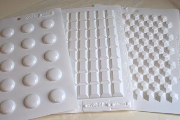 5. Kẹo pha lê. Nguyên liệu: Đường cát, siro ngô, nước, giọt màu thực phẩm, thìa chất tạo vị. Đổ tất cả các nguyên liệu làm kẹo (trừ dầu tạo vị) vào nồi, khuấy đều. Cho nhiệt kế thực phẩm vào nồi (đừng để nhiệt kế chạm đáy nồi). Bật bếp lửa to. Ảnh: baomoi.com.