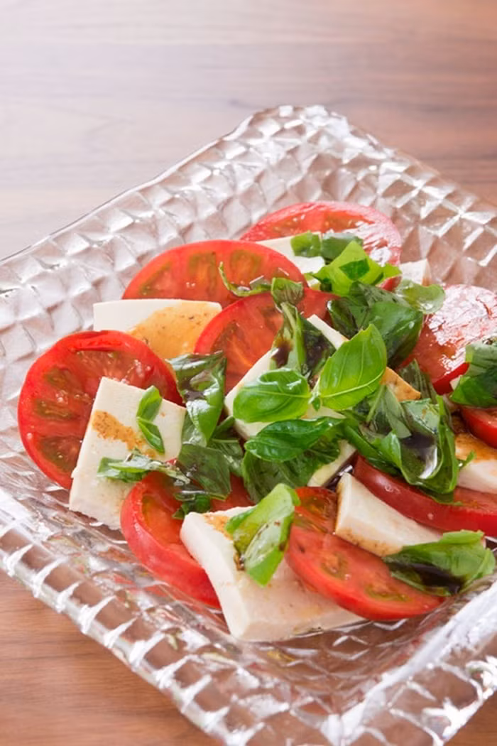 Salad đậu phụ và cà chua. Nguyên liệu cần chuẩn bị gồm cà chua, chanh, muối, dầu ô liu, giấm, húng quế. Đầu tiên cắt đậu phụ thành miếng và vắt chanh, rắc muối đều lên cả hai mặt đậu phụ. Cho đậu phụ vào ngăn mát tủ lạnh và không đậy khoảng 5 tiếng để muối ngấm và ráo nước. Ảnh: Norecipe.