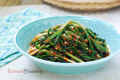 Lấy lá hẹ ra khỏi bát to. Phần nước mắm còn sót lại trộn với hỗn hợp bột nếp đã nguội. Khuấy đều cùng với bột ớt. Sau đó thêm hành tây, lá hẹ vào, trộn thật đều. Rắc vừng lên, trộn lần nữa là được. Ảnh: Eva.vn.