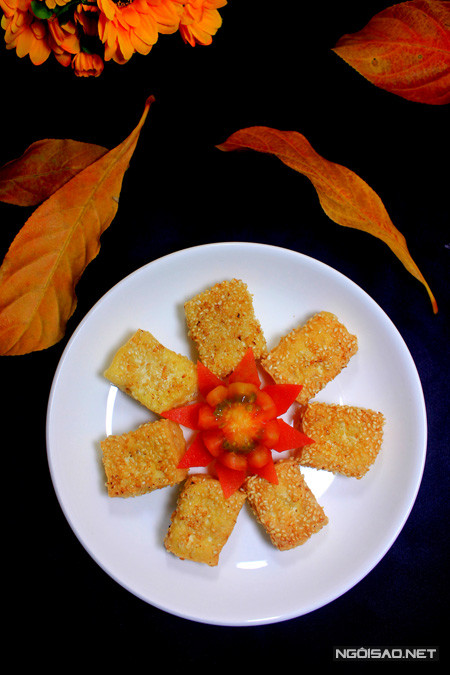 5. Đậu phụ tẩm vừng chiên giòn. Nguyên liệu: Đậu phụ, vừng, bột chiên giòn, dầu ăn, hạt nêm. Đậu phụ rửa sạch, dùng khăn thấm khô sau đó cắt đậu thành miếng vừa ăn. Cho bột chiên giòn vào bát cùng một ít hạt nêm, thêm nước vào hòa tan thành hỗn hợp sền sệt. Nhúng từng miếng đậu phụ vào bột chiên giòn. Tiếp đó lăn đậu phụ qua vừng sao cho vừng áo đều miếng đậu. Đun nóng dầu ăn trong chảo, cho đậu phụ vào chiên ngập dầu cho đến chín vàng là được, sau đó cho đậu ra đĩa có lót giấy thấm dầu là xong. Ảnh: ngoisao.net.