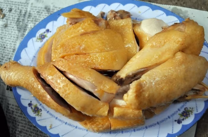 Nước trong nồi sôi, thì mới cho gà vào, nước chưa ngập gà cũng không sao. Đậy nắp nấu tiếp chừng 10 phút, bật qua chế độ hâm và để khoảng 25 phút nữa. Nhấc gà ra nhúng vào thau nước đá. Bước này để da gà được giòn. Ảnh: Emdep.