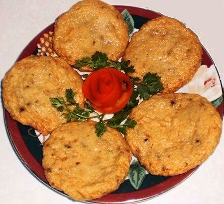 Cầm hết cá lên tay và đập xuống tô vài lần để cá được dai. Phần bột và trứng: cho bột mì, bột bắp vào tô, đập trứng vào lấy muỗng khuấy đều. Cho cá đã ướp hành, ngò cắt nhỏ nhào chung với bột. Trộn đều hỗn hợp trên. Cho ít dầu ăn thoa lên đĩa. Bắt chả cá thành từng cục và ép mỏng. Chiên chả cá với dầu nóng. Ảnh: amthuc365.com.