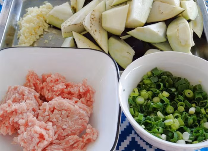 5. Cà tím xào tỏi. Nguyên liệu gồm cà tím, thịt nạc băm, hành lá. Cà tím rửa sạch lau khô và nướng nguyên trái trên bếp cho cà sém vỏ rồi cắt đôi. Thịt băm đem ướp với hành và các gia vị khoảng 10 phút. Rửa sạch hành lá và thái thật nhỏ. Ảnh: Tin247.