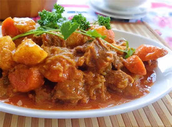 3. Bò hầm khoai tây. Nguyên liệu: Thịt bò, khoai tây, cà rốt, cà chua, ngũ vị hương, tiêu, hành, mùi. Rửa thịt sạch rồi thái quân cờ, ướp với hạt tiêu, hạt nêm và 1/2 gói ngũ vị hương. Xào săn và chế nước, hầm bằng nồi áp suất sao cho thịt nhừ vừa tới. Khoai tây nạo vỏ, bổ miếng vừa ăn. Cà chua bổ làm tư, cà rốt tỉa hoa xắt khúc. Chưng cà chua với chút dầu ăn để tạo màu. Cho khoai tây, cà rốt vào xào ngấm mắm ngấm muối. Múc thịt bò vào nồi khoai tây rồi ninh đến khi khoai và cà rốt chín bở cũng là lúc thịt bò chín nhừ. Rắc hành, mùi thái nhỏ vào nồi rồi tắt bếp. Ảnh: toinayangi.vn.