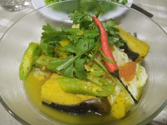 Cho cá đuối vào xào cho đến khi cá săn lại thì cho ít nước vào đun. Cho dứa, cà chua vào, nêm gia vị. Đun nhỏ lửa. Cho đậu bắp và chuối xanh vào sau cùng. Nấu thêm 3 phút nữa là được. Ăn kèm với bún. Ảnh: PipiCity.com.