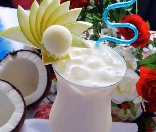 Rót sinh tố dừa tươi ra ly, chia đôi phần thạch dừa ra 2 ly sinh tố, cho thêm đá bào vừa đủ dùng lên trên, rưới vài đường sữa đặc chéo nhau trên đá bào cho đẹp mắt. Gắn lát chanh tươi lên thành ly sinh tố dừa tươi. Ảnh: eva.vn.