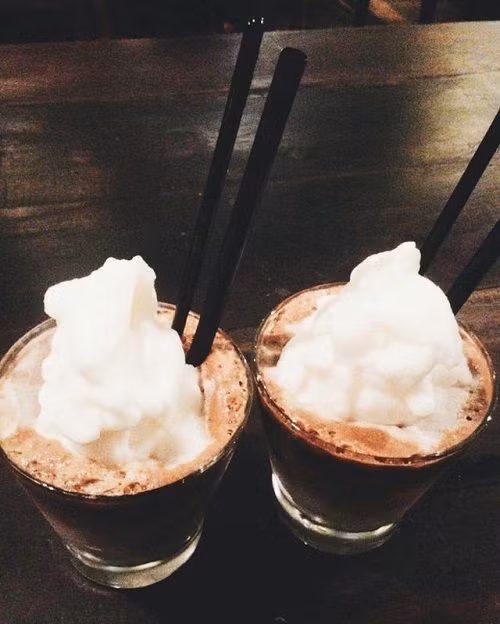 Khi cà phê chảy hết bạn thêm sữa và nước dừa vào. Cũng có thể biến tấu thêm cả nước cốt dừa và dừa nạo vào để thức uống thơm ngon và lạ. Cho đá viên vào ly và rót cà phê nước dừa vào, rắc lên trên 1 chút ca cao. Ảnh: blog.beemart.vn.