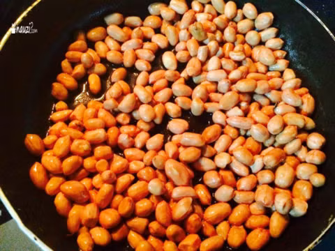 Cứ rang như vậy từ 7-9 phút, các hạt lạc bắt đầu tách ra, tuy nhiên vỏ lạc vẫn chưa bong hẳn ra thì cho khoảng 1 - 1/5 thìa dầu vào, đảo tiếp. Vẫn để lửa nhỏ để dầu ăn ngấm dần vào lạc. Như vậy lạc sẽ rất giòn và bùi. Ảnh: Nauzi.com.