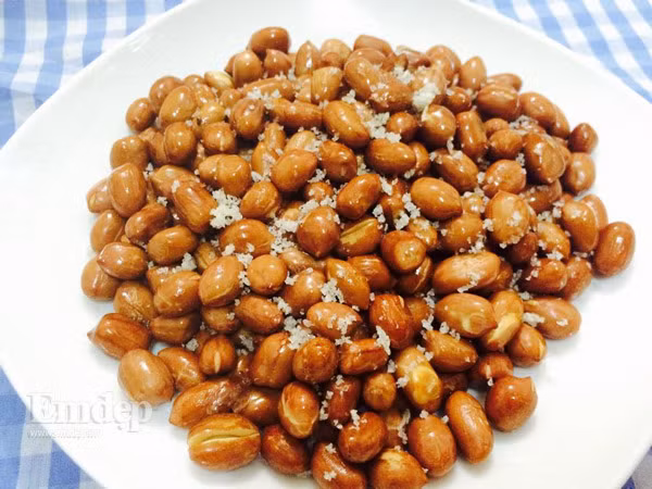 Nếm hạt lạc thấy lạc chín, có vị bùi bùi, và hơi giòn là được. Khi lạc chín vàng, đều, cho ra ngoài, để nguội nhưng tay vẫn đảo đều. Khi lạc chưa nguội hoàn toàn (vẫn còn hơi ấm), cho bột canh vào rồi đảo đều để bột canh bám xung quanh lạc. Ảnh: kenhphunu.com.