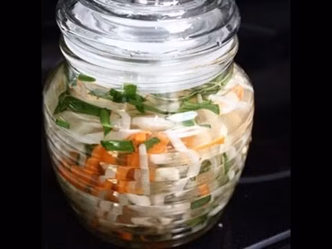 Pha ba muỗng canh đường, hai muỗng nhỏ muối, một muỗng nhỏ giấm và bốn muỗng canh nước lọc, khuấy để đường tan. Nêm hơi chua chua ngọt ngọt và vừa. Trộn cà rốt, hẹ, giá vào với nhau. Ảnh: youtube.com.