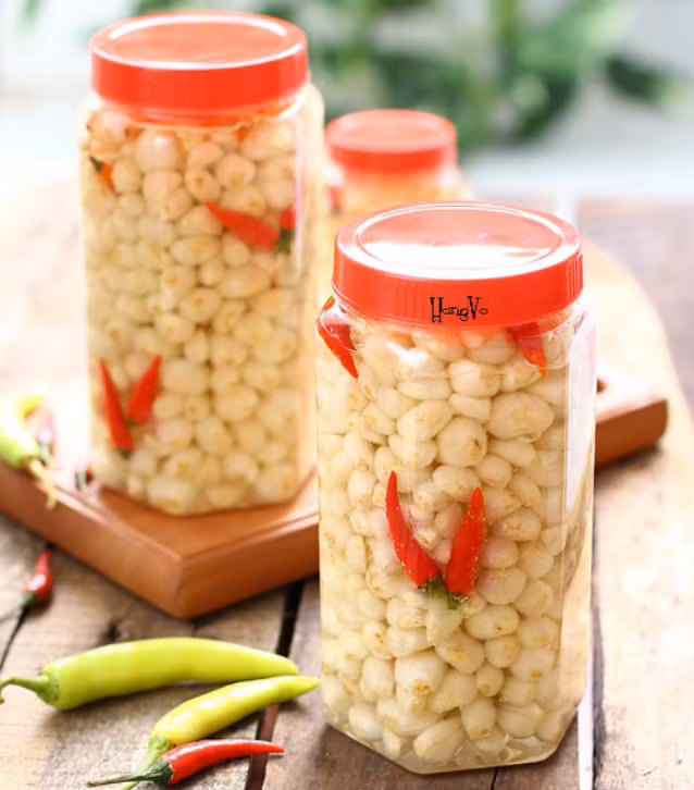 Vớt kiệu ra, cắt bỏ rễ, lột lớp vỏ bên ngoài rồi ngâm vào nước vôi trong trong khoảng 2 tiếng. Sau đó vớt ra và phơi kiệu ngoài nắng cho đến khi hơi héo bề mặt là được. Cà rốt gọt vỏ, tỉa hoa. Sau đó cũng đem phơi ngoài nắng đến khi hơi héo bề mặt giống kiệu. Ảnh: cachnauan.edu.vn.