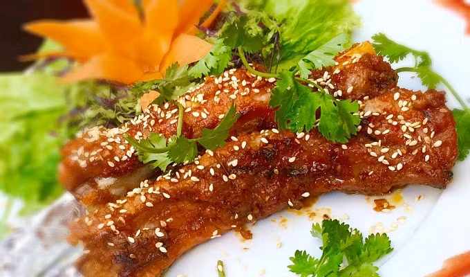 Rạch đường chéo song song vào phần thịt sườn đã rửa sạch rồi ướp với sa tế, hạt tiêu, mật ong, hành khô, nước mắm, dầu oliu trong 20 phút. Nướng sườn trên bếp than hoa đến khi sườn dần ngả sang màu cánh gián là được. Ảnh: ElinerFood.com.