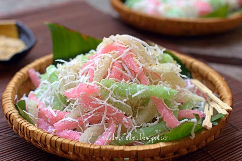 Hấp bánh: Khuôn thoa dầu ăn, đổ từng phần khoai mì vào, dùng tay ấn dẹp xuống bề mặt khuôn. Đun nồi nước sôi, hấp riêng từng khuôn khoai mì, đến khi khoai mì có màu trắng trong là đã chín. Để nguội, cắt thành từng lát dài cỡ lóng tay giữa hoặc thành từng miếng vuông vừa ăn. Lăn những miếng khoai mì qua hỗn hợp dừa bào vụn. Làm nước cốt: Cho đường, chút muối, 1 muỗng cafe bột năng, bắc lên bếp nấu sôi với lửa nhỏ đến khi hỗn hợp nước cốt dừa đặc sánh lại thì tắt bếp. Lấy bánh tằm ra đĩa, rưới ít nước cốt dừa lên trên, rắc thêm chút mè đậu phộng (nếu thích) ăn kèm. Ảnh: tasteathomecooking.com.