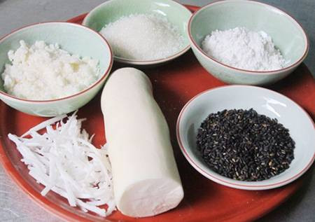 3. Bánh tằm khoai mì. Nguyên liệu: Khoai mì, cùi dừa, lá cẩm, củ dền, lá dứa, bột năng, đường, muối, dầu ăn. Khoai gọt vỏ, rửa sạch khoai mì, ngâm qua đêm hoặc ngâm 5- 6 tiếng trong thau nước lạnh có pha chút muối. Bào khoai mì thật mịn. Vắt khoai mì thật ráo nước, lọc qua rây, phần nước vắt từ khoai mì đã lọc để trong tô khoảng 15 phút cho lắng bột xuống, đổ hết nước ra, giữ lại phần tinh bột. Dừa nạo nhỏ, 1/3 để rắc lên bánh, phần còn lại cho nước sôi vào, ngâm 1 lúc rồi vắt lấy nước cốt dừa. Ảnh: dulichdalat365.com.