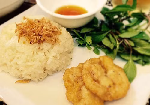 Gạo ngâm xong đem đãi sạch, trộn đều với 1 thìa cà phê hạt nêm và đường rồi cho vào nồi hấp, hấp chín. Khi xôi đã chín thì cho xôi ra đĩa, cắt chả mực thành những miếng vừa ăn đặt lên xôi. Món xôi chả mực này đảm bảo ai cũng mê. Ảnh: Healthplus.vn.