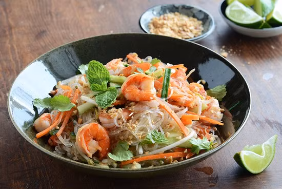 Pha nước trộn gỏi: hòa 2 muỗng mật ong với 1 bát ăn cơm nước lọc ấm sau đó thêm 2,5 muỗng nước mắm, 2 muỗng giấm vào khuấy đều, cuối cùng thả gừng thái nhỏ, ớt băm vào trộn đều. Khi ăn sắp bún vào tô, xếp cà rốt, dưa chuột, giá đỗ, rau thơm, rắc lạc rang lên trên rồi rưới nước mắm chua ngọt. Ảnh: imonanngon.info.