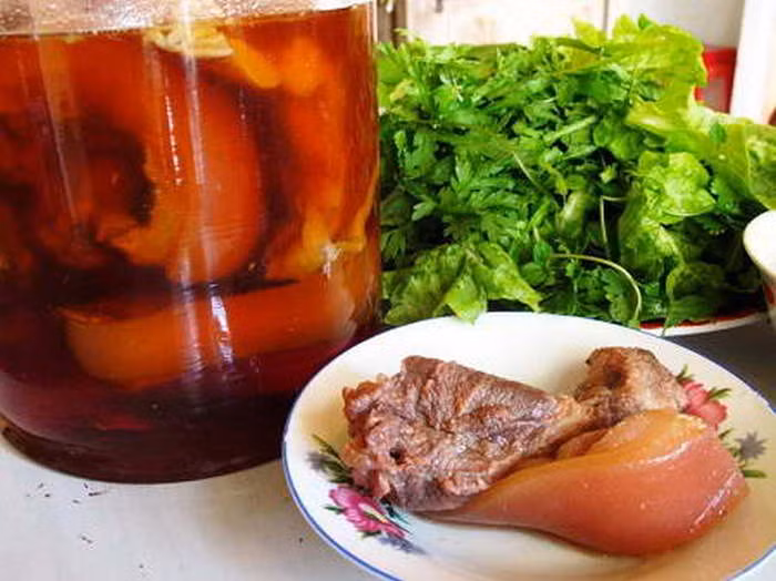 Nấu nước mắm: Cho mắm, đường, nước vào nồi nấu khoảng 15-20 phút. Cho thịt chân giò đã luộc chín, tỏi cắt lát và ớt vào lọ thủy tinh. Sau đó đổ nước mắm ngập và dùng mành tre gài lại rồi đậy kín. Sau 3 ngày có thể thưởng thức món ngâm mắm này. Ảnh: Monanngon.