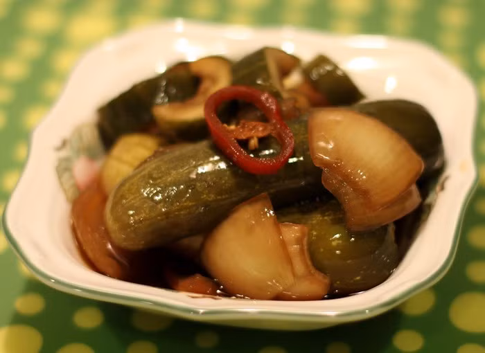 Cho muối vào ngâm dưa leo khoảng 2-3 giờ đồng hồ sau đó vớt để ráo nước. Ớt rửa sạch, tỏi bóc vỏ thái lát. Cho ¼ bát con nước mắm và ½ bát con đường cát trắng vào nồi đun sôi để nguội. Xếp dưa leo vào lọ thủy tinh sạch, thêm nước mắm, ớt quả, tỏi vào. Ảnh: Doisongphapluat.