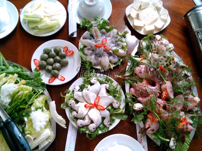 Bày nồi lẩu cá ra, giữa xếp cá, rau bên cạnh, đợi nước lẩu sôi thì thả cá vào. Khi ăn, nhúng kèm rau. Ảnh: foody.vn.