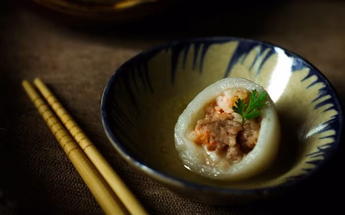 Tôm bóc vỏ băm nhuyễn, trộn cùng thịt đã xay sẵn. Thêm hành lá, hẹ thái nhỏ, hành khô băm, tỏi băm vào. Cho thêm 2 thìa cà phê hạt nêm, 1/2 thìa dầu mè, 1 muỗng canh dầu ăn, 1 thìa tiêu, 1 thìa đường và 1 thìa bột năng. Trộn đều hỗn hợp. Ảnh: Monngonmoingay.