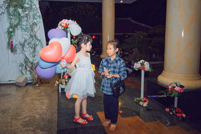 Bức ảnh được chụp tại một đám cưới cũng làm người xem ngậm ngùi. Một cô bé chừng 6-7 tuổi mặc váy trắng xúng xính tay cầm bóng bay, chân mang giày đỏ lộng lẫy. Bên cạnh đó là một cô bé bán vé số, ăn mặc rất đơn giản và khuôn mặt cơ cực. Thêm bố cục của bức ảnh bé gái đứng trên, em bé bán vé số đứng dưới bậc càng khiến cho bức ảnh nổi bật ý nghĩa. Ảnh: Hồ Trọng Phi.