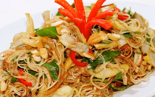 Cho bắp chuối, hành tím, ớt chuông vàng và đỏ, cần tây, ớt sợi, đậu hũ ky vào tô, rưới nước mắm vào trộn đều cho thấm gia vị, thêm hạt điều vào trộn. Ảnh: cacmonchayngon.net.