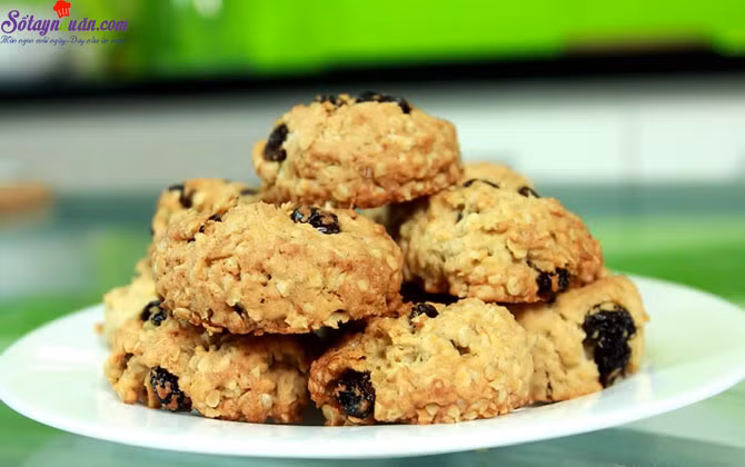 Sau đó trộn yến mạch, socola vào. Dùng tay nặn hình hoặc dùng 2 cái muỗng tạo hình như mong muốn trên khay nướng. Sau đó nướng 9-10 phút hoặc 12-13 phút nếu muốn bánh giòn. Để trên khay nướng cho nguội khoảng 1 phút, sau đó để nguội hoàn toàn. Ảnh: sotaynauan.com.
