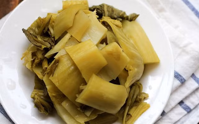 Dưa muối vắt sạch nước. Cà chua xắt múi cau. Hành tươi thái nhỏ, hành khô đập dập. Phi thơm hành khô, cho cà chua và dưa muối vào xào thơm, xào khoảng 2 phút đổ một lượng nước vừa đủ vào. Sau đó đợi đến khi nước sôi già, bạn có thể cho cá trê vào. Ảnh: Cooky.vn.