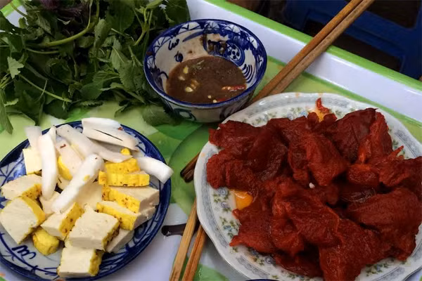 5. Gỏi sứa đỏ. Sứa cắt thành những tảng lớn, ngâm trong nước hãm làm từ cây sú vẹt. Khi ăn, bạn lấy một chiếc lá tía tô và kinh giới, đặt lên trên một miếng sứa, một miếng đậu nướng, một miếng dừa non, cuộn lại và chấm với mắm tôm. Miếng sứa biển thanh mát, giòn giòn kết hợp với miếng đậu phụ nướng mềm bùi, cùi dừa béo ngậy đem lại cảm giác mới lạ đầy thú vị. Một chút mắm tôm đánh kỹ với quất và ớt tươi cùng với rau kinh giới, tía tô giúp món ăn càng đậm đà hơn. Ảnh: giadinh.net.vn. 