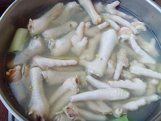 Bắc nồi nước lên bếp, đập dập 2 củ sả cho vào nồi đun. Nước sôi già thì trút hết chân gà vào luộc. Khi nồi luộc chân gà sôi bùng lên, vớt ngay chân gà ra ngâm nước đá, chân gà sẽ chín tới và giòn. Sau đó vớt chân gà ra cho vào tủ lạnh. Ảnh: mevacon.com.vn.