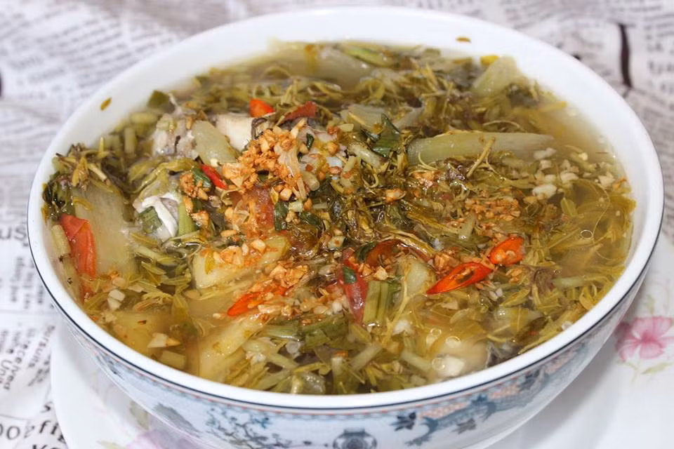 Nước sôi khoảng 3 phút, cá sắp chín tới, bạn cho cà chua, đậu bắp, dọc mùng, giá đậu, lá me non vào. Nêm thêm muối, đường, hạt nêm sao cho vừa ăn. Khi thấy món canh đã chín tới, tắt bếp, cho rau thơm và hạt tiêu vào. Ảnh: goccuabep.com.