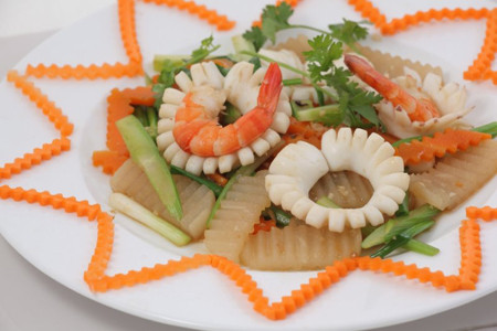 Phi thơm hành, tỏi, cho mực và tôm vào xào tới khi săn lại thì cho cà rốt và củ cải vào xào cùng, nêm muối, đường, hạt nêm, nước vào xào 3 phút thì thêm hành lá, tắt bếp. Ảnh: chacom.net.