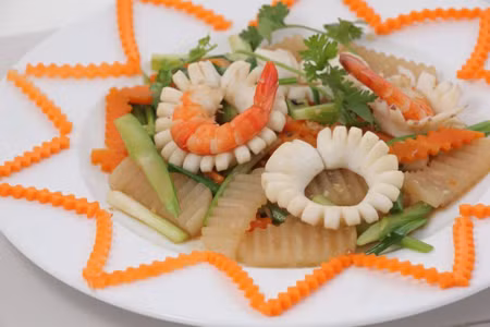 Phi thơm hành, tỏi, cho mực và tôm vào xào tới khi săn lại thì cho cà rốt và củ cải vào xào cùng, nêm muối, đường, hạt nêm, nước vào xào 3 phút thì thêm hành lá, tắt bếp. Ảnh: chacom.net.