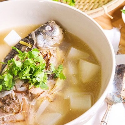 Cho cá chép và củ cà rốt vào trước. Khi nước canh sôi lần 2 thì cho củ cải trắng vào. Vớt bỏ bọt canh để nước canh trong. Nêm gia vị, cho hành lá, ớt băm và ngò rí vào. Tắt bếp, rắc tiêu lên trên. Ảnh: Cooky.vn.