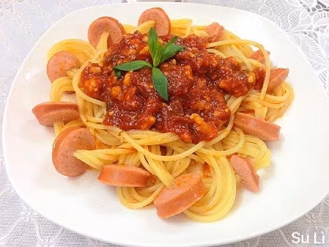 Đun nước sôi và thả mỳ vào trần qua. Cho dầu vào và phi tỏi thật thơm lên. Sau đó cho tiếp hành tây đã băm nhuyễn vào đảo cùng. Tiếp theo cho xúc xích vào rồi đổ sốt cà lên. Cho ngay mỳ vào, đảo lên, th.m gia vị vừa đủ, độ 5-10 phút là được. Lúc bắc ra nhớ rắc hạt tiêu cho thơm. Ảnh: youtube.com.