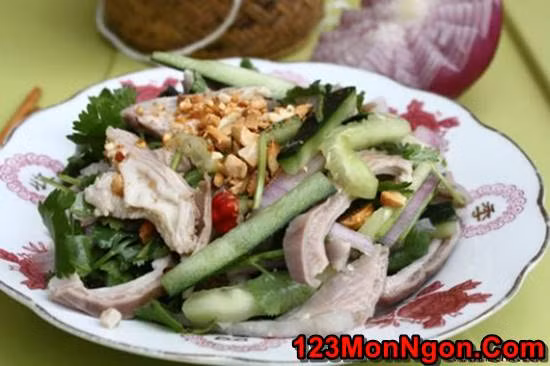 Pha nước mắm, đường, tỏi và ớt băm thành hỗn hợp nước chấm. Trộn đều dưa leo, hành tây, dạ dày lợn với hỗn hợp nước chấm và nước cốt chanh, giấm. Sau đó trộn thêm rau thơm vào cùng và rắc lạc rang lên trên cùng. Ảnh: 123monngon.com.