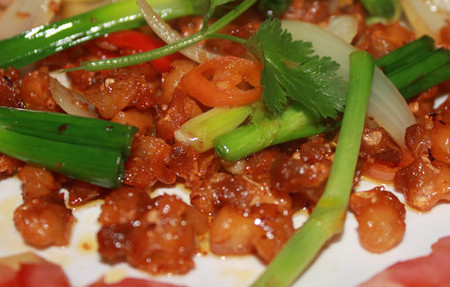 Tỏi băm nhuyễn, phi vàng rồi trộn đều cùng hỗn hợp nước mắm, đường, bột ngọt. Cho sụn gà và hỗn hợp trên vào chảo, đảo nhanh tay cho đến khi nghe mùi thơm. Tắt bếp, cho gà ra đĩa, trang trí cho đẹp cùng cà chua cắt lát mỏng. Ảnh: nhungmonanngon.com.