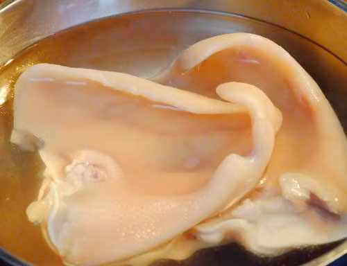 3. Tai heo ngâm mắm. Nguyên liệu: Tai heo, nước mắm, đường, giấm, nước lạnh, sả, muối, hành tây, nước cốt chanh, đường phèn, hành, ớt, tỏi. Tai heo rửa qua nước có pha chút muối, sau đó rửa lại bằng nước lạnh. Ảnh: wikimonngon.com